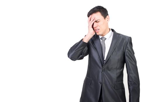 Exhausted male office worker wearing classy suit feeling pain in head touching face and frowning face with closed eyes in studio against white background
