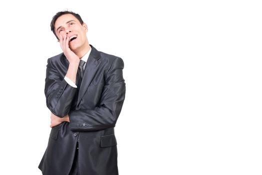 Enamored man in formal suit keeping hand on cheek and looking up dreamily against white background