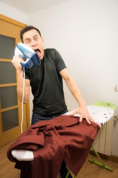 Man who does not know how to iron clothes, trying unsuccessfully to iron a shirt at home. Mid shot.