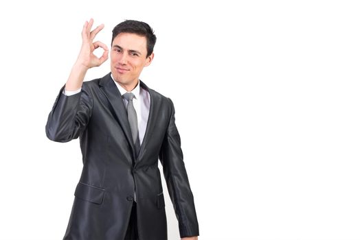 Successful male entrepreneur in formal suit showing OK gesture and looking at camera isolated on white background in light studio