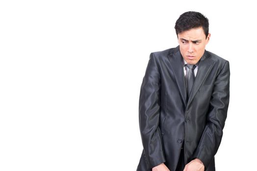 Afraid young male manager with dark hair in elegant suit with scared face looking away cautiously against white background