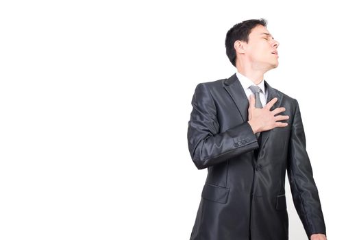 Unpleasant male in elegant wear with closed eyes touching chest with hand while suffering isolated on white background in light studio