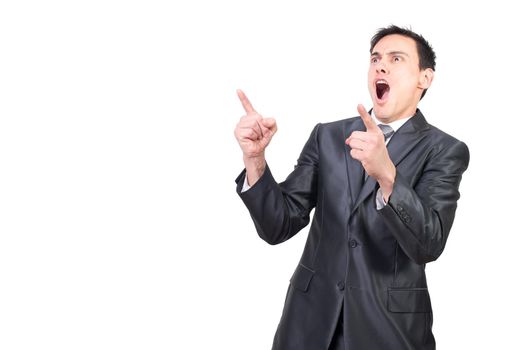 Cheerful young male manager with dark hair in formal suit shouting happily and pointing away while celebrating success against white background