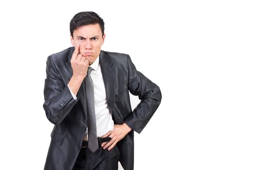 Serious man in formal suit pointing at eye while keeping control and looking at camera with concern against white background