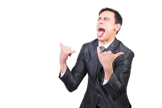 Cheerful mature male with closed eyes and open mouth wearing formal black suit showing little finger and thumb showing rock gesture against white background