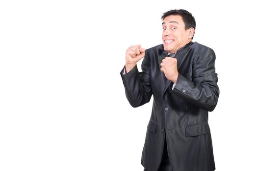 Positive male in formal suit looking at camera with clenched fists while celebrating achievement isolated on white background in studio