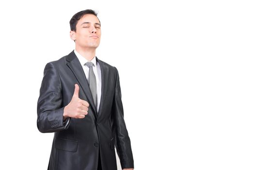 Successful male in formal suit looking at camera while showing thumb up gesture isolated on white background in light studio