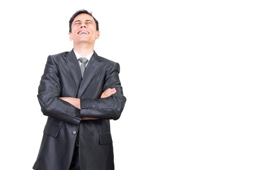 Positive male in formal suit laughing with closed eyes while standing with crossed arms isolated on white background in studio