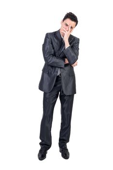 Full length of bored young male entrepreneur with dark hair in formal suit covering face with hand and looking at camera against white background