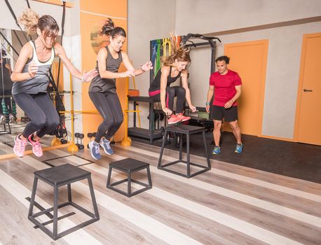Sportswomen doing box jumps at gym with trainer. Concept of exercise on gym.