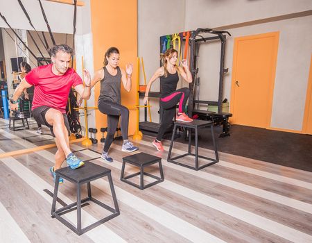 Male and female athletes doing box lunges in gym. Concept of exercise on gym.