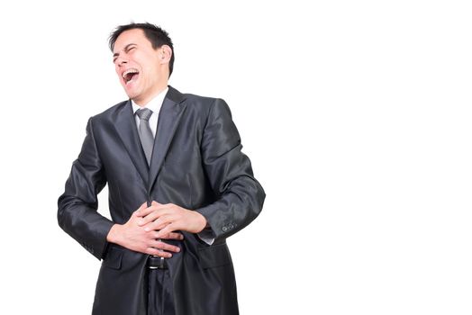 Cheerful adult male with closed eyes wearing formal black suit laughing and touching belly while standing against white background