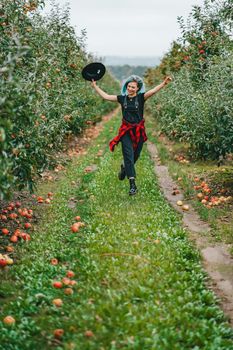 Pretty unusual woman with blue dyed hair walking alone between trees in apple garden at autumn season. Girl goes ahead away from camera. Organic, nature concept. High quality FullHD footage