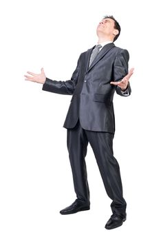 Full length of sad suffering man in elegant suit with dark hair standing in white studio with hands apart and closed eyes