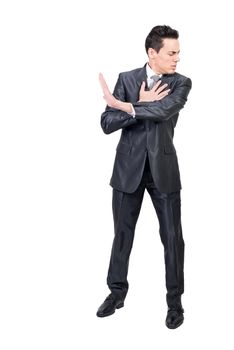 Full body of male entrepreneur in suit and with hurt feelings touching chest and showing stop sign on white background in studio