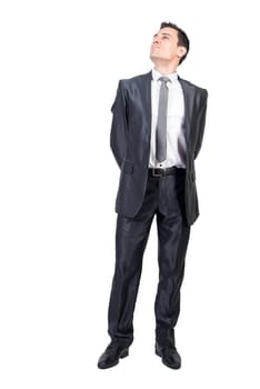 Full body of ambitious male manager wearing classy suit standing on white background and dreamily looking up