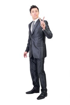 Full body of male in elegant suit showing victory gesture and making kiss grimace in studio against white background