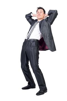 Full body of funny male model in formal outfit raising hands behind back while relaxing in studio against white background