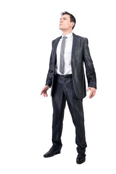 Full body of dignified male in elegant suit looking into distance while standing isolated on white background in light studio