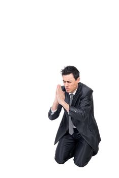 Full body of male in suit with prayer hands closing eyes while begging for help and kneeling in studio on white background