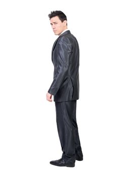 Side view full body of seductive male entrepreneur in classy suit standing in studio against white background and looking at camera