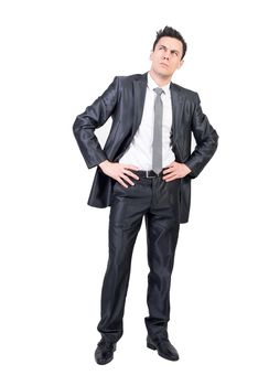 Full body of pondering male manager in suit standing with hands on waist and looking up with expression of doubt in studio against white background