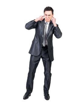 Full body of annoyed male manager in formal suit expressing anger and covering ears from loud noise in studio against white background