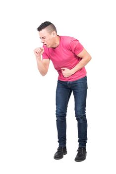 Full body ill male in pink t shirt and jeans touching stomach and coughing with closed eyes isolated on white background