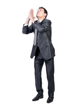 Full body of male entrepreneur in formal suit keeping hands together and pleading for help against white background in studio