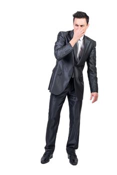 Full body of well dressed male entrepreneur holding nose with fingers and sniffing nasty smell on white background in studio