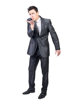 Full body of flirting male in formal suit sending air kiss and looking at camera isolated on white background in light studio