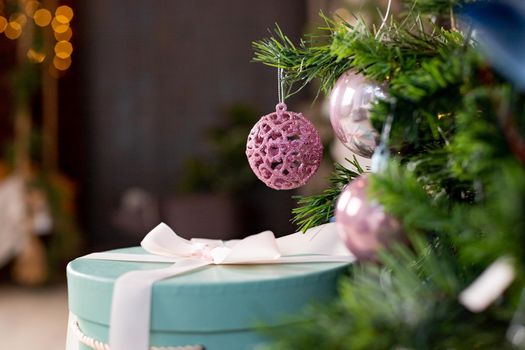 Silver and pink bauble hanging on a decorated snow tree. Christmas holiday background.