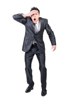 Full body of astonished male in formal suit looking at camera with hand on forehead isolated on white background in studio