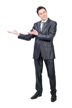 Full body of positive male in elegant suit pointing aside and looking at camera while showing ad isolated on white background