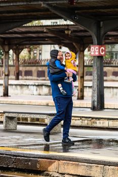 Tourist pulling luggage. Commuters walking at railroad station platform in Bucharest, Romania, 2022