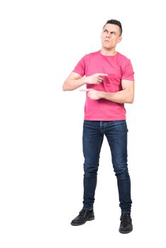 Full body confused man in casual clothes pointing in different directions and looking up while making difficult decision against white background