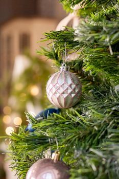 Silver and pink bauble hanging on a decorated snow tree. Christmas holiday background.