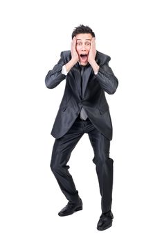 Full body of shocked young businessman with dark hair in formal outfit touching cheeks and screaming against white background