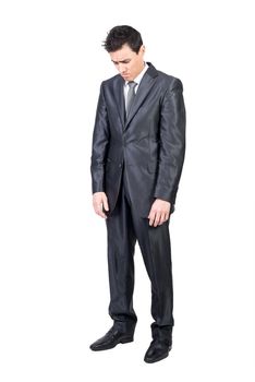 Full length of melancholic young male entrepreneur with dark hair in formal gray suit and tie looking away pensively while standing isolated on white background
