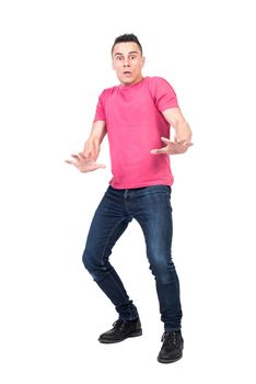 Full length scared male in jeans and pink t shirt looking at camera and staggering back from danger isolated on white background