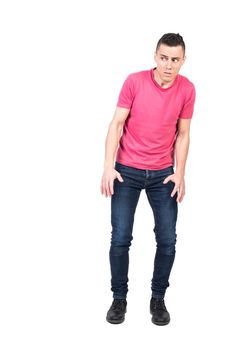 Full body afraid male in jeans and pink t shirt peeking and checking danger with caution against white background