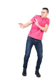 Full length worried man in jeans and pink t shirt making protective gesture and staggering back from danger isolated on white background