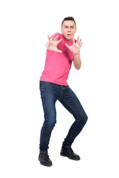 Full body afraid male in casual clothes making protective gesture and looking at camera against white background