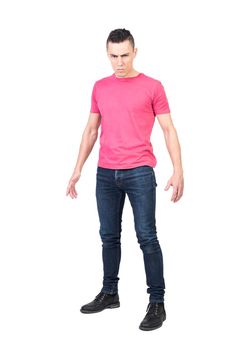 Full body man in jeans and pink t shirt frowning and challenging camera against white background