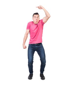 Full body of male model in casual wear peeping and pointing aside while standing isolated on white background in light studio