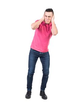 Full body of annoyed male with unpleased expression covering ears from loud noise on white background