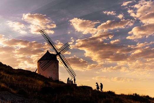 Photo with coopy space of people walking around an ancient windmill in a hill during sunset in Consuegra, Spain
