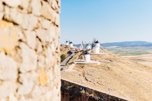 Selective focus on a group of historic windmills on a hillside with fields in the background the image