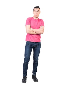 Full body of astonished male in casual clothes looking into distance while standing with crossed arms isolated on white background