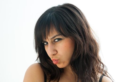Very serious pretty brunette girl pulling a kiss and staring, over white background, close up